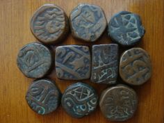 six ancient coins are arranged on a wooden surface