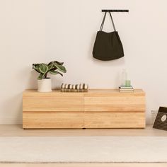 a wooden dresser with a black purse hanging on it's sideboard next to a potted plant