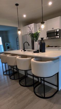 a kitchen island with four stools in front of it and a vase on the counter