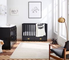 a baby's room with black and white furniture, an elephant print wall hanging above the crib