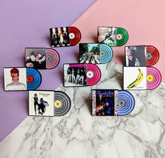 several different colored records are arranged on a marble counter top with pink and purple background