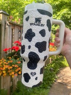 a hand holding a coffee cup decorated with black and white spots