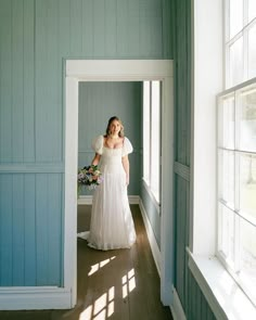 a woman in a white dress is walking down the hall way with her bouquet on her head