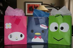 three paper bags with faces on them sitting on a table in front of a lamp