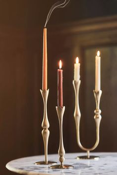 three candles on a table with one lit and the other turned off in different directions