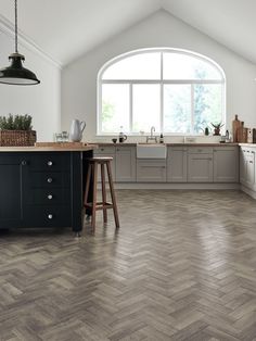 a large kitchen with an island in the middle and wood flooring on the other side