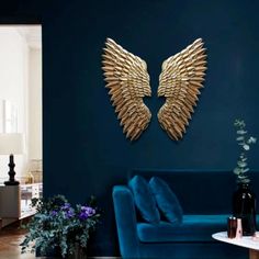 a living room with blue couches and gold wings on the wall