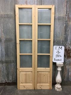 two wooden doors sitting next to each other in front of a metal wall with a sign on it