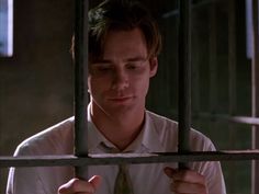 a man in a white shirt and tie behind bars