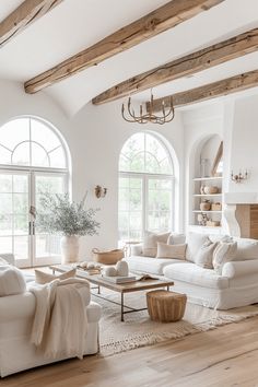 a living room filled with white furniture and large arched windows in front of two huge windows