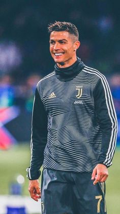 a man standing on top of a soccer field wearing a black and white uniform with gold stripes