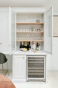 an open cabinet with wine glasses and bottles in it