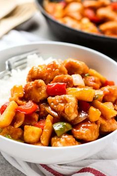 a white bowl filled with chicken and vegetables on top of rice next to a skillet