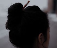 a woman with her hair in a bun is looking out the window on a snowy day