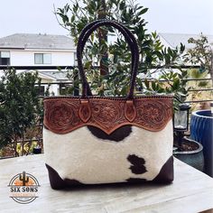 a brown and white purse sitting on top of a table next to a potted plant