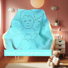 a blue crocheted blanket sitting on top of a wooden floor next to a teddy bear