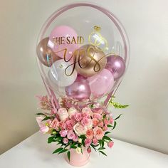 a vase filled with balloons and flowers on top of a table