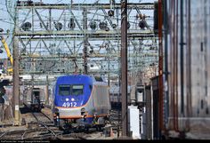 a blue and silver train traveling down tracks next to another train on it's track