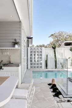 an outdoor kitchen and pool area with white furniture