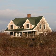 a large white house sitting on top of a lush green field next to tall grass