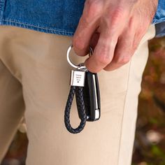 a man holding onto a black and silver keychain