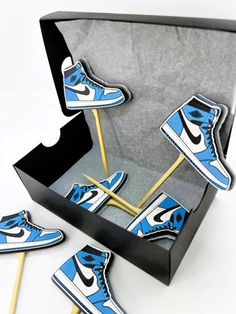 blue and white sneakers on top of sticks in a box with black cardboard backings