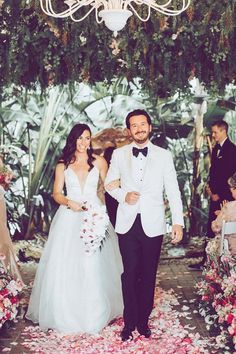 a bride and groom are walking down the aisle at their wedding in front of an elaborate chandelier