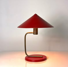 a red table lamp sitting on top of a white counter