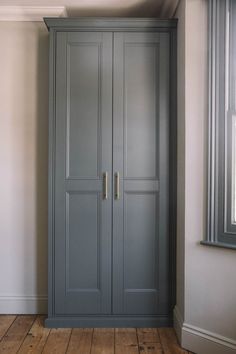 an empty room with a large gray cabinet in the corner and wood flooring on the other side