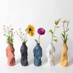 four different colored vases with flowers in them