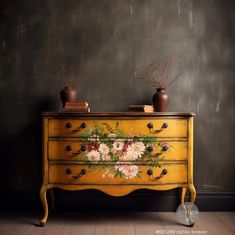 an old dresser with flowers painted on the side and two vases sitting on top