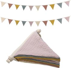 a stack of blankets sitting on top of each other under a bunting line with flags in the background