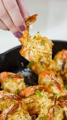 a person is dipping some food into a skillet with shrimp and cheese on it