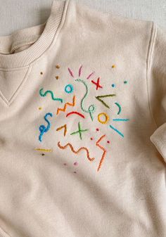 a white sweater with colorful letters and numbers on it