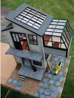 a small model house is shown in the middle of a yard