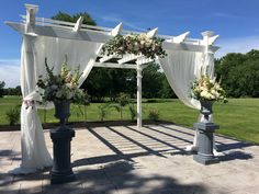 an outdoor wedding setup with white drapes and flowers