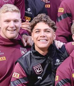 a group of young men standing next to each other in maroon shirts and black pants