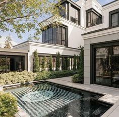 an outdoor swimming pool in the middle of a house with lots of windows and doors