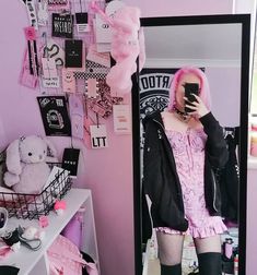 a woman with pink hair is taking a selfie in front of a mirror and holding a cell phone