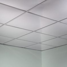 an empty room with white walls and square tiles on the ceiling is seen in this image