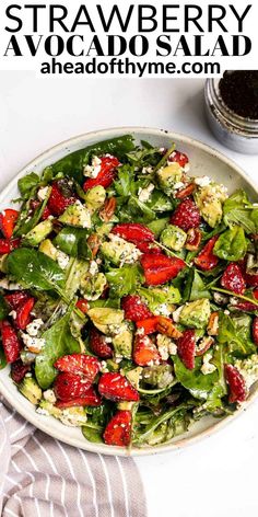 strawberry avocado salad with feta cheese and spinach in a white bowl