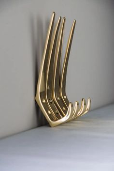 a set of five gold forks sitting on top of a white counter next to a gray wall