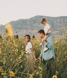 a man, woman and child walking through a field of sunflowers