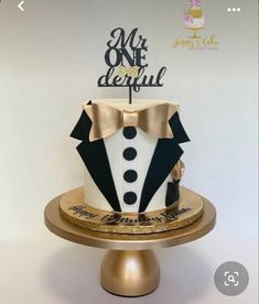 a cake decorated with a tuxedo and bow tie on a gold plated stand