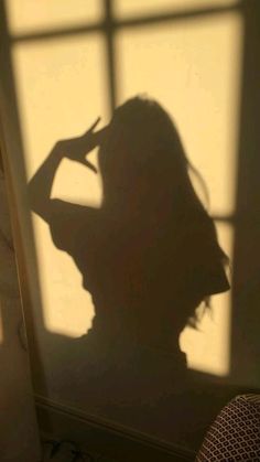 the shadow of a woman standing in front of a window with her hands on her head