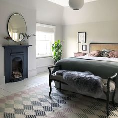 a bedroom with a bed, fireplace and mirror