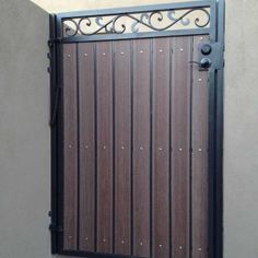 an iron gate with wooden slats on the side of a building in front of a stucco wall