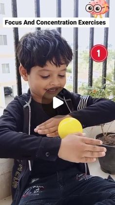 a young boy sitting on the ground holding a yellow ball