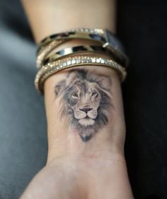 a woman's wrist with a lion tattoo on it