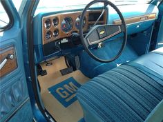 the interior of an old truck with blue leather seats and steering wheel covers on it